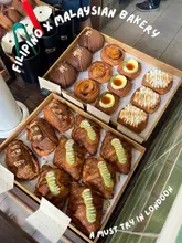 A top-down, high-angle shot showcasing a variety of pastries arranged in wooden trays inside a bakery display case at Mahalia & Co in London.