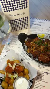 A promotional video showcasing a £5 meal deal at Frankie & Benny's, featuring shots of the restaurant exterior, interior, menu, and various food items like pizza, burgers, chicken wings, and cauliflower bites.