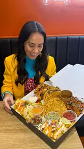 A review of a 'Birria Box' from Birria Boyz in Leeds, showcasing the variety of items included such as tacos, loaded fries, mac and cheese, and wings. The video highlights the food's quality and the convenience of the takeaway/delivery option, while also mentioning the new sit-in location.