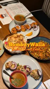 A short-form video review of BombayWalla in Glasgow, featuring a montage of various Indian street food dishes including noodles, chicken tikka, and malabar porotta, alongside shots of the restaurant's interior and exterior.