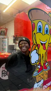 A creator visits The Fat Pizza, showcasing the takeaway venue, the ordering process, and a variety of food items including a 24-inch pizza, burgers, chicken wings, curly fries, and desserts, while mentioning watching football.