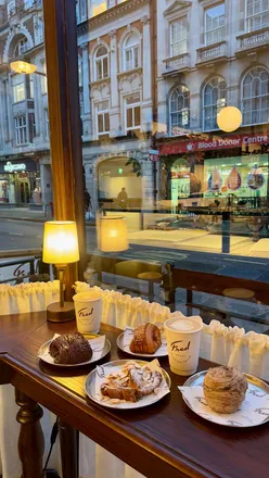 Two foodies enjoying flaky pastries at Fred Bakery, known for delicious, generous fillings and a cozy atmosphere.