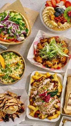 Delicious food from Newport Market including tacos, souvlaki, smoothies, and desserts enjoyed in a vibrant indoor setting.