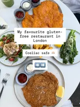 A bright, well-composed overhead flat-lay photograph showcasing a spread of food including schnitzel, a burrata salad, and broccolini, used to promote a gluten-free restaurant in London.