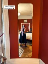 A mirror selfie taken in a boutique hotel room, showcasing the interior design and the creator's stay. The image captures the aesthetic of the room, including the red walls and wooden flooring.