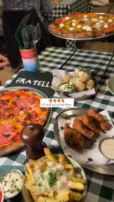 A promotional video for Fratelli, a pizza restaurant in Bury, featuring a montage of various pizzas, sides like arancini and wings, and shots of the venue's interior and exterior.