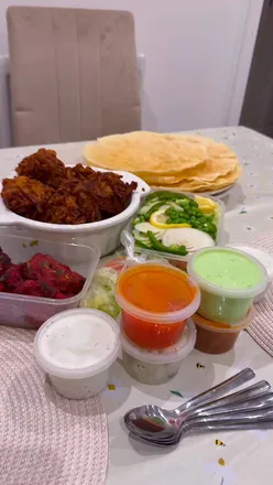 Delicious Indian takeaway spread featuring tandoori lamb chops, onion bhajis, naans, and chutney at Turmeric Gorseinon.