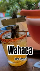 Hot Honey & Pickle and Rhubarbarita margaritas on a table with tacos, quesadillas, and taquitos at Wahaca.