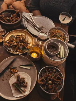 Diners enjoying flavorful dishes at Fatt Pundit, showcasing momos, spicy wings, and noodles in London.