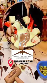 An array of chocolate desserts: a sphere, cheesecake, and waffle, with drinks at Myra Chocolate London in Little Venice, London.