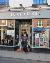 A photo of a creator standing in front of the 'Slice + Dice' board game cafe and bar in Norwich. The image serves as an introduction to a review of the venue, showing the storefront and the creator.