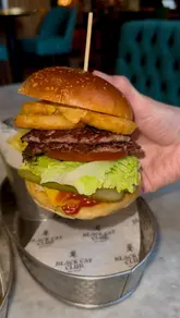 Diners eating a beef burger with onion rings and a hot honey chicken burger with fries at Black Cat Clubs, Exchange Flags, Liverpool.