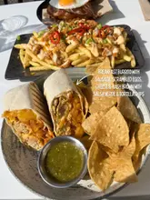 Customers enjoy outdoor brunch on a sunny day at Casa Glasgow, featuring a delicious breakfast burrito. Gluten-free friendly restaurant.