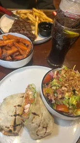 A promotional video for TGI Friday's 'Everyday Trio' menu, showcasing the variety of food and drink options available for a set price. The video features close-up shots of the menu, various dishes like corn ribs, wraps, steak, and desserts, and the dining experience.