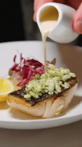 A high-quality, cinematic montage showcasing the plating of various dishes and the interior of Orion restaurant. The video focuses on the artistry of the food preparation and the elegant atmosphere of the venue.
