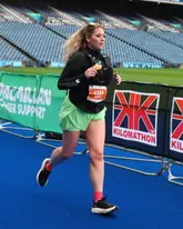 A candid action shot of a runner participating in the Kilomathon event at a stadium.