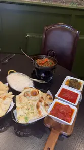 A creator visits The Bengal Table in Sunderland with her father, reviewing a variety of dishes including poppadoms, mixed kebabs, onion bhajis, aloo vada, railway lamb, chicken tikka masala, and chicken sagwala.
