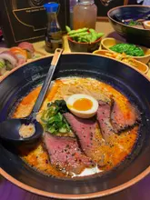 A spread of Maki & Ramen Japanese dishes: Soft Shell Crab & Rainbow sushi rolls, Steak Tataki, and Hell Ramen.