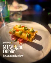 A moody, well-composed food shot featuring a pair of spring rolls, likely from a gastropub review. The lighting is atmospheric, typical of a restaurant setting, and the focus is sharp on the subject.