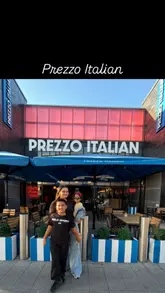 Here are a few options for your SEO alt text, depending on what the image shows:

**Option 1 (Focus on the meal):**
Family enjoying a delicious dinner of pizza, pasta, and desserts at Prezzo Italian in Milton Keynes Stadium.

**Option 2 (Focus on the kids):**
Kids eating at Prezzo Italian in Milton Keynes, enjoying a family meal with pasta, pizza, and dessert.

**Option 3 (Focus on the brand/experience):**
The family-friendly dining experience at Prezzo Italian restaurant located in the Milton Keynes Stadium.

**SEO Tip:** If the photo is of a specific dish, make sure to mention the food name (e.g., "Sticky toffee pudding and pizza at Prezzo Italian").