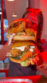 A short, punchy review of a fried chicken restaurant, featuring close-up shots of crispy chicken strips being dipped in sauce and a burger being eaten. The creator shares their reaction to the spice level and quality of the food.