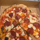 Freshly baked pepperoni pizza slice with honey drizzle at Marco's Pizza Mia stall in Kidbrooke, London.