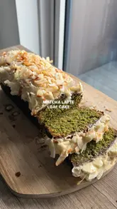 Green matcha loaf cake topped with creamy white chocolate glaze & toasted coconut. Sliced to reveal its vibrant interior.