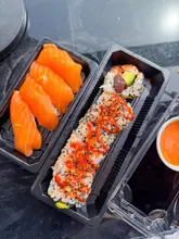 Here are a few options for your SEO alt text, all under 125 characters:

*   **Option 1 (Descriptive):** Fresh salmon nigiri and spicy tuna avocado uramaki sushi rolls served at Sooshi in Mermaid Quay, Cardiff Bay.
*   **Option 2 (Action-oriented):** A delicious sushi lunch featuring salmon nigiri and spicy tuna rolls at Sooshi restaurant in Cardiff Bay.
*   **Option 3 (SEO-focused):** Fresh high-quality sushi rolls and nigiri from Sooshi, a popular takeaway spot in Mermaid Quay, Cardiff.