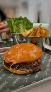 A promotional video showcasing a collaboration between Heard and Akoko, featuring burgers, spiced fries, and ice cream sandwiches. The video uses quick, polished cuts to highlight the food items and the venue's interior and exterior.