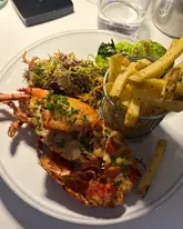 Here are a few options for your SEO alt text, depending on the focus of the image:

**Option 1 (Descriptive & SEO-focused):**
"A delicious spread of Isle of Wight seafood, including miso grilled lobster, tempura prawns, and cocktails by the coast."

**Option 2 (Broad/Travel focus):**
"Food tour of the Isle of Wight featuring fresh lobster, prawns, cocktails, and scenic seaside dining at The Hut."

**Option 3 (Concise):**
"Culinary highlights from the Isle of Wight including fresh seafood dishes, a prawn baguette, and summer cocktails."

**SEO Tip:** If the image is a collage, using words like "food tour," "seafood," and "Isle of Wight" will help you rank for local food and travel searches.
