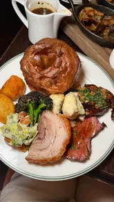 Here are a few options for your SEO alt text, depending on what is most prominent in your photo:

**Option 1 (Focus on the sharer board):**
Generous Sunday roast sharer board with beef, pork, lamb, crispy roast potatoes and Yorkshire puddings at The George.

**Option 2 (General vibe/location):**
A delicious, stacked Sunday roast dinner with bone marrow gravy served at The George London pub.

**Option 3 (More descriptive of the components):**
Crispy roast potatoes, massive Yorkshire puddings and a meat sharer board for a Sunday roast at The George, London.

**SEO Tip:** I recommend **Option 1 or 3** as they include the specific search terms people use when looking for food recommendations ("Sunday roast," "sharer board," "roast potatoes," and "Yorkshire puddings").