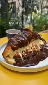 Here are a few options for your alt text, keeping it under 125 characters:

**Option 1 (Descriptive):** 
A decadent Badiani dessert featuring a warm croissant topped with chocolate sauce and a scoop of gelato.

**Option 2 (Action-oriented):** 
Close-up of a Badiani 1932 gourmet dessert with a flaky croissant, chocolate drizzle, and artisanal gelato.

**Option 3 (Concise):** 
Delicious Badiani London dessert with a buttery croissant, chocolate sauce, and premium gelato scoop.
