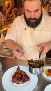 Here are a few options for your alt text, depending on how descriptive you want to be:

*   **Descriptive:** Chef Meedu Saad presenting signature roasted duck with molasses and fig sauce at Impala Soho.
*   **Action-oriented:** Chef Meedu Saad plating his signature molasses-roasted duck with a rich fig sauce at Impala Soho.
*   **Concise:** Signature molasses-roasted duck with fig sauce served by Chef Meedu Saad at Impala Soho.

**Recommendation:** The first option is the strongest for SEO as it includes the Chef's name, the dish name, and the restaurant name clearly.