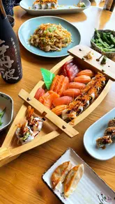 Assortment of fresh sushi, including nigiri and maki rolls, beautifully presented in a boat from Sakura Leicester.