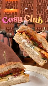 A review of the new spring menu at Cosy Club in Manchester, featuring a variety of dishes including small plates, sandwiches, and desserts. The creator highlights specific items like the hot honey halloumi focaccia, arancini, and the brûléed miso caramel tart.
