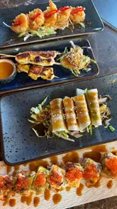 Here are a few options for your SEO alt text, keeping it under 125 characters:

**Option 1 (Focus on experience):**
Chef performing a live teppanyaki cooking show with fire at Teppan3 restaurant in Belfast.

**Option 2 (Focus on food variety):**
Delicious spread of fresh sushi, teppanyaki, and Japanese dishes at Teppan3 Belfast restaurant.

**Option 3 (Concise):**
Live teppanyaki cooking experience and Japanese food served at Teppan3 in Belfast.

**SEO Tip:** I recommend **Option 1** if the image shows the chef cooking, as "Teppanyaki" and "Belfast" are your strongest keywords here.