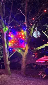A vibrant montage showcasing a street food festival held in a wooded area, featuring various food stalls, cocktails, and live cabaret entertainment.