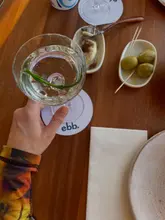 A clean, well-composed, and aesthetically pleasing shot of a cocktail and small plates on a wooden table, effectively capturing the atmosphere of a modern restaurant.