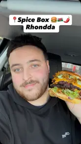A creator reviews a large 'munch box' from Spice Shack, a takeaway operating out of a rugby club in Rhondda. The video features close-ups of various Indian-fusion items including burgers, chicken tenders, tandoori wings, and sides, with the creator providing commentary on the flavours.