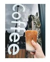 A simple, effective shot of an iced coffee held against a cafe window, serving as a visual for a listicle about Glasgow coffee spots.