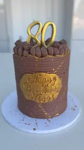 Here are a few options for your SEO alt text, depending on what the image focuses on:

**Option 1 (Descriptive & SEO-focused):**
"An elegant 80th birthday cake with gold accents and candles, handcrafted for a milestone celebration."

**Option 2 (Focus on the style):**
"A beautifully decorated 80th birthday cake featuring signature piping and custom cake toppers."

**Option 3 (Short & punchy):**
"Custom 80th birthday cake with gold luster dust and elegant candles for a milestone celebration."

**SEO Tip:** I included "80th birthday cake" and "milestone celebration" as these are high-traffic search terms for people looking for cake inspiration.