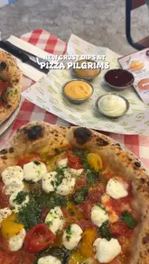 Here are a few options for your SEO alt text, keeping under the 125-character limit:

**Option 1 (Descriptive):**
Pizza Pilgrims pizza with new collaboration crust dips from Dishoom, Pho, Sweet Dee’s, and Honest Burgers.

**Option 2 (Action-oriented):**
Dipping a pizza crust into new collaborative dips from Pizza Pilgrims at Grand Central, Birmingham.

**Option 3 (Concise):**
Close up of Pizza Pilgrims pizza served with four new limited-edition collaboration crust dips. 

**SEO Tip:** I recommend **Option 1** as it includes the brand name and the specific collaborative partners, which helps with search visibility.