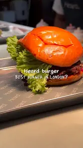 A short, punchy montage showcasing a burger restaurant. The video features the exterior of the venue, a close-up of a burger being cut, the cooking process on a flat-top grill, and a toast with cocktails, highlighting the quality of the food and the dining experience.