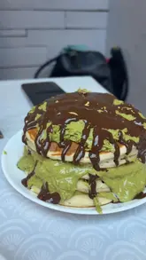 Here are a few options for your alt text, depending on what is most important to highlight:

**Option 1 (Descriptive & SEO-focused):**
"Stack of fluffy pancakes topped with Dubai chocolate and pistachio sauce at Hidden Gem Cafe in Bellshill."

**Option 2 (Action-oriented):**
"Close-up of decadent Dubai chocolate-style pancakes being served at Hidden Gem Cafe, Bellshill."

**Option 3 (Short & Punchy):**
"Indulgent Dubai chocolate trend pancakes served at Hidden Gem Cafe in Bellshill."

**SEO Tip:** Including the location (**Bellshill**) and the business name (**Hidden Gem Cafe**) is the best way to help local customers find your content!
