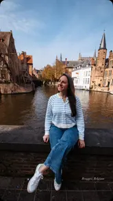 Here are a few options for your SEO alt text (all under 125 characters):

**Option 1 (Descriptive):**
Scenic view of historic medieval buildings and a winding canal in Bruges, Belgium during a luxury river cruise.

**Option 2 (Keyword-focused):**
Picturesque cobblestone streets and medieval architecture along a canal in Bruges, Belgium.

**Option 3 (Travel-focused):**
Travelers exploring the historic UNESCO World Heritage city of Bruges, Belgium on a scenic river cruise.

**SEO Tip:** If the image shows a specific landmark (like the Belfry tower) or people, I recommend using **Option 1** as it provides the most helpful context for both search engines and accessibility tools.