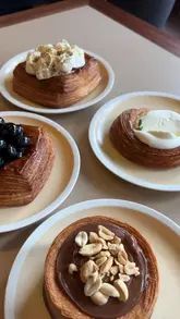 A short review of Milk Run bakery in South London, featuring a variety of pastries including olive oil and mascarpone, blueberry, cheesecake, and chocolate tart, alongside a matcha latte.