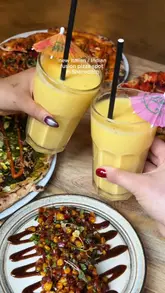 Here are a few options for your SEO alt text, keeping it under 125 characters:

**Option 1 (Descriptive & SEO-focused):**
Chicken tikka masala pizza, lobster arancini, and mango lassi served at East West London restaurant in Shoreditch.

**Option 2 (Action-oriented):**
Diners enjoying an Italian-Indian fusion pizza and street food meal at East West London in Shoreditch.

**Option 3 (Concise):**
Delicious chicken tikka masala pizza and Indian fusion appetizers at East West London restaurant, Shoreditch.

**Tip:** Including the restaurant name ("East West London") and the location ("Shoreditch") is the most important part for local SEO!
