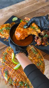 A promotional video for Taco House in Hackney, featuring close-up shots of birria tacos, a large birria pizza, and chicken wings. The video also provides a brief tour of the venue, showcasing the interior seating, arcade games, and outdoor waterside dining area.
