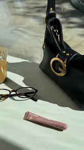 Here are a few options for your alt text, keeping it under 125 characters and SEO-friendly:

**Option 1 (Descriptive & Brand-focused):**
A woman wearing a stylish Guess Camden bag while holding an iced coffee during a cafe outing in London.

**Option 2 (Fashion-focused):**
Close-up of a trendy Guess shoulder bag being carried on a coffee run in the city.

**Option 3 (Lifestyle-focused):**
A stylish casual outfit featuring a Guess Camden bag and an iced coffee on a sunny day in London. 

**SEO Tip:** Always include the brand name (Guess) and the product style (Camden bag) as these are the keywords people are most likely to search for!