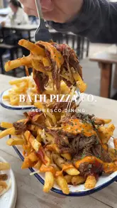 Here are a few options for your SEO alt text (all under 125 characters):

**Option 1 (Descriptive & SEO-friendly):**
Table of pizzas, loaded brisket fries, and calamari at Bath Pizza Co in a sunny outdoor setting.

**Option 2 (Focus on the meal):**
Delicious lunch spread featuring Hawaiian pizza, truffle fries, and beef brisket fries at Bath Pizza Co.

**Option 3 (Concise):**
Al fresco lunch at Bath Pizza Co featuring gourmet pizzas, loaded fries, and calamari.